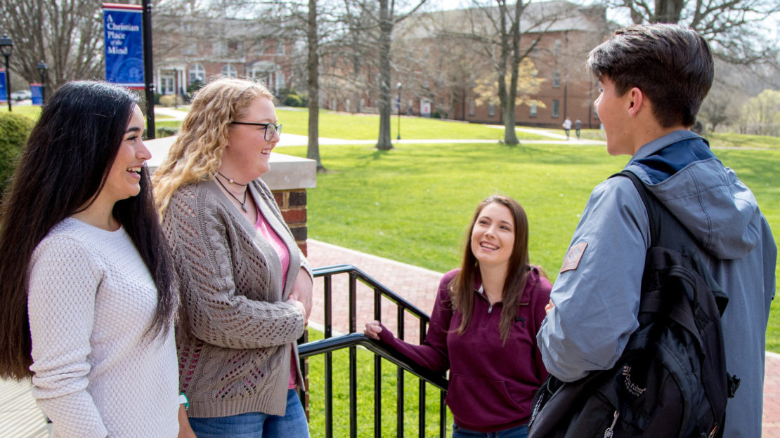 four students outside chatting