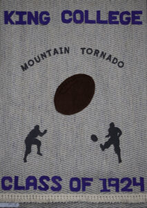 A woven banner reads KING COLLEGE CLASS OF 1924 with MOUNTAIN TORNADO above a brown football and two black silhouettes of football players, set against a textured background.