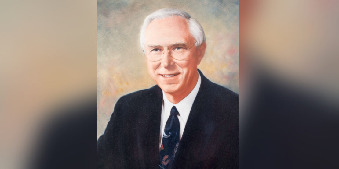 A formal painted portrait of an older man with short white hair and glasses, wearing a dark suit, white shirt, and patterned tie, set against a softly blurred background.